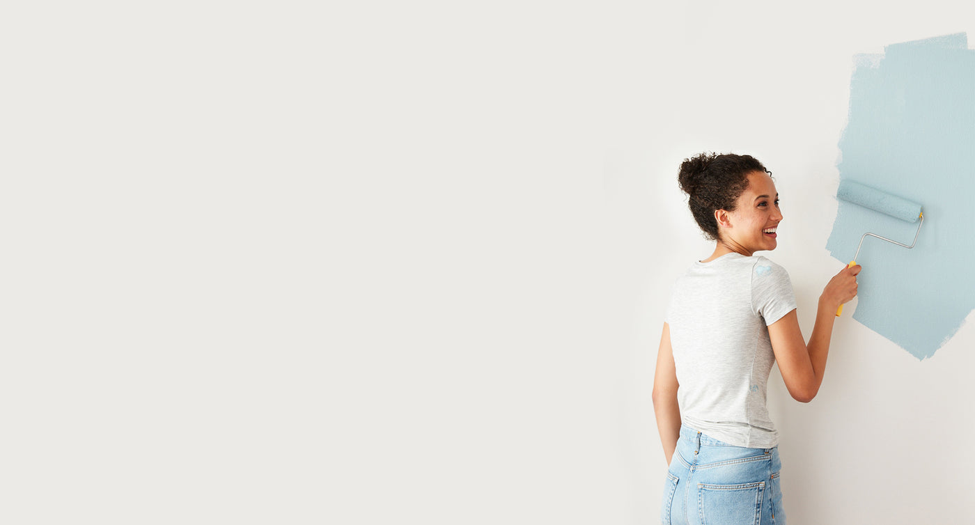 Woman painting blue on the wall.